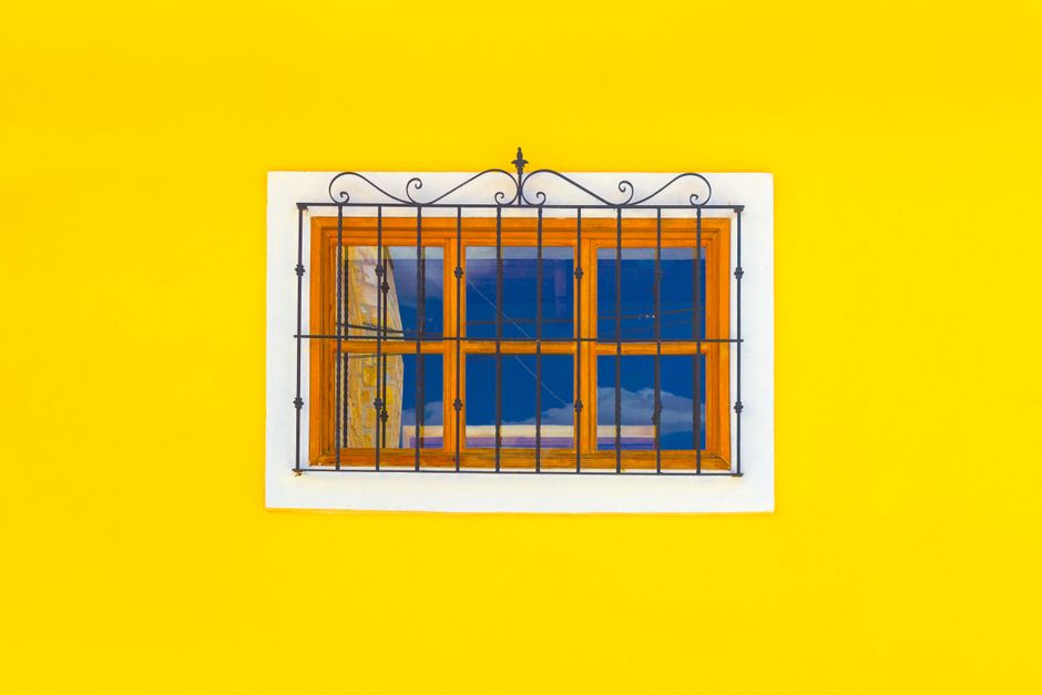 A small wooden window frame set in a yellow painted wall.