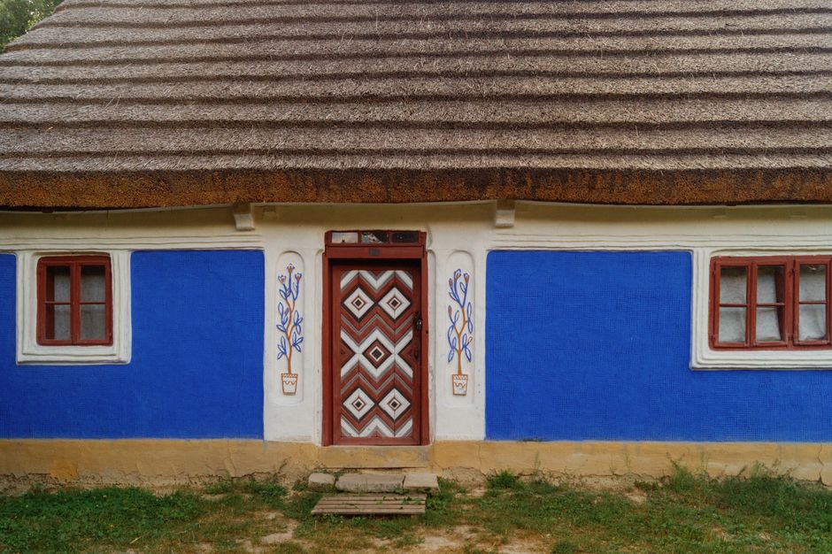 A small house with painted blue walls and a thatched roof.